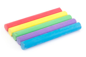 Row of rainbow color chalk on white
