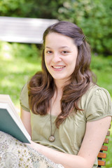 junge Frau bließt ein Buch im Garten
