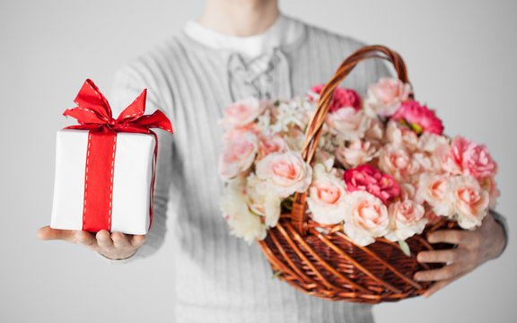 man holding basket full of flowers and gift box