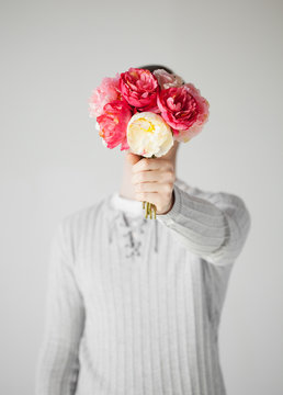 man covering his face with bouquet of flowers
