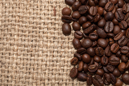Coffee grains on rough fabric of linen close-up