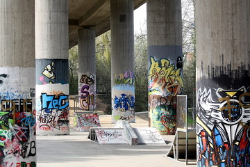 Grafitti an Säulen einer Brücke mit Skaterpark