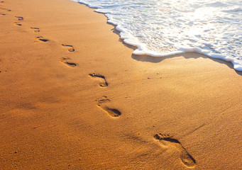 Plakat plaża, fala, a kroki w czasie zachodu słońca