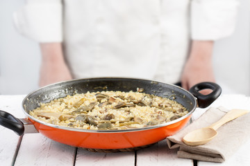 Cook standing behind a pan on vegetables rice