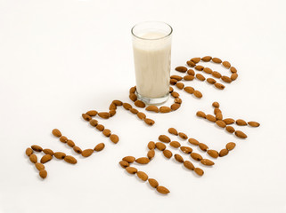 Almond milk and several almonds on a white background