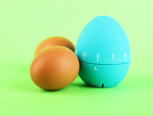 Blue egg timer and eggs, on color background