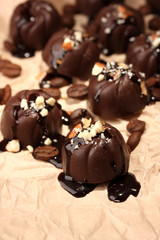 Chocolate candies and coffee beans, on beige paper background