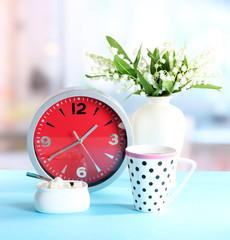 Cup tea and clock on bright background