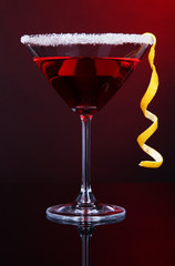 Red cocktail in martini glass on dark red background