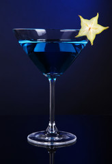 Blue cocktail in martini glass on dark blue background