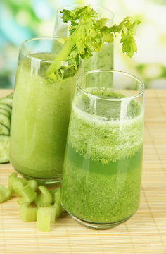 Glasses of green celery juice on bamboo mat, on green