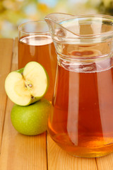 Full glass and jug of apple juice and apples