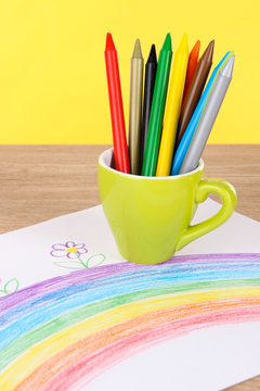 Colorful pencils in cup on table on yellow background