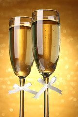 Two glasses of champagne on bright background with lights