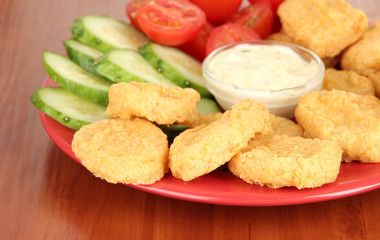 Fried chicken nuggets with vegetables and sauce on table