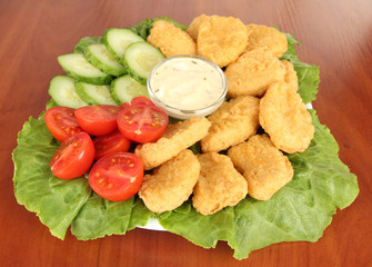 Fried chicken nuggets with vegetables and sauce on table