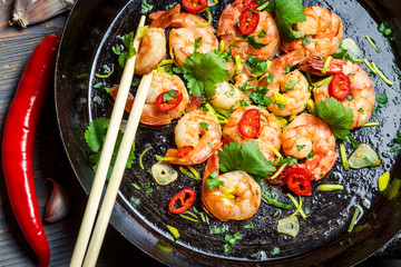 Shrimps sauteed with chilli pepper on old black pan