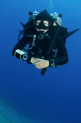 Fotobehang girl scuba dives in clear blue water with twin tanks © JonMilnes