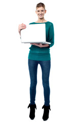 Full length shot of smiling girl holding laptop