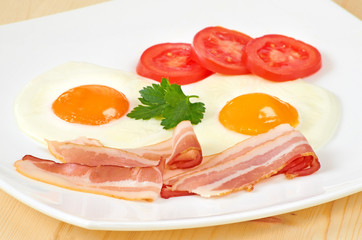 Breakfast with bacon,  fried eggs and slices tomatoes