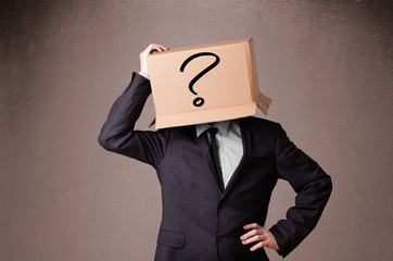 Businessman gesturing with a cardboard box on his head with ques