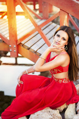 Beautiful brunette woman in red dress outdoors