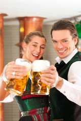 Man and woman with beer glass in brewery