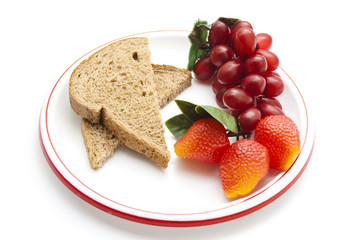 Plastik Trauben und Erdbeeren mit  Vollkornbrot auf Teller