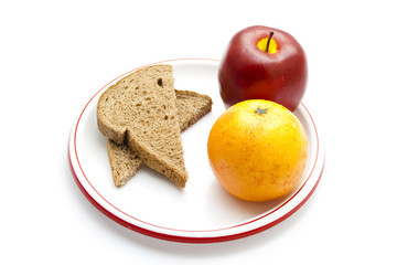 Fototapeta na wymiar Plastik Apfel mit Orange und Vollkornbrot auf Teller