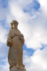 Fototapeta na wymiar Angelic Statue with fluffy blue clouds and sky.