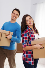 Happy couple carrying boxes in their new home