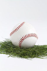baseball on cut grass in white studio.