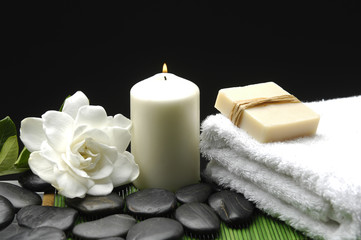 stones with soap on towel and candle on green mat