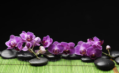 Obraz na płótnie Canvas pink orchid with black stones on green mat