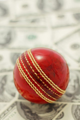 Red cricket ball and money