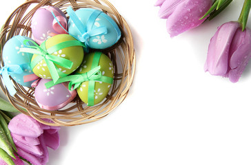 Bright easter eggs in basket and tulips, isolated on white