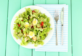 Caesar salad on white plate, on color wooden background