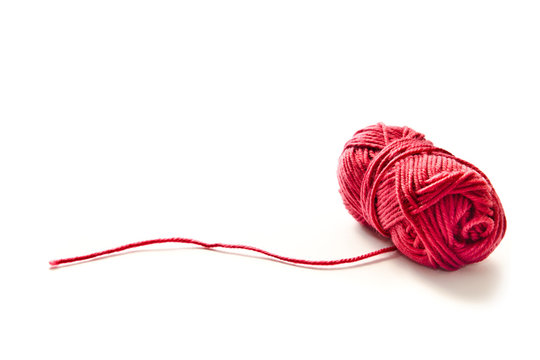Ball of red yarn with a loose string stretching to the side on a gray  background with copy space Stock Photo by wirestock