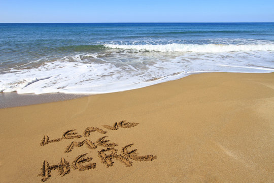 Leave me here written on golden sandy beach