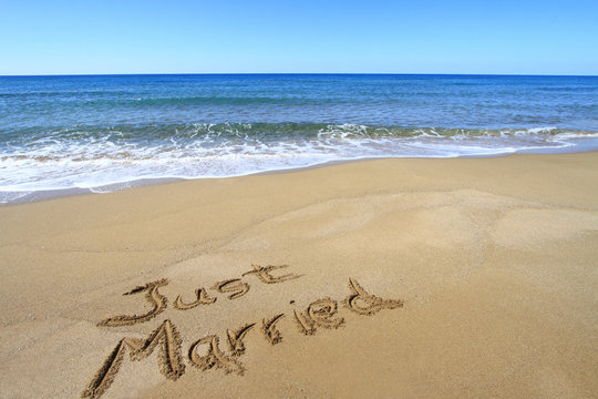 "Just married" written on golden sandy beach