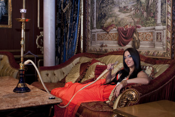 Obraz na płótnie Canvas Beautiful oriental dressed woman with hookah