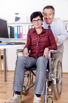 Man helps a wheelchair user in the office