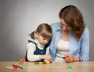 Naklejka premium Young mother and her dauther modelling with plasticine