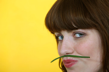 Woman holding a green bean between her lips and her nose
