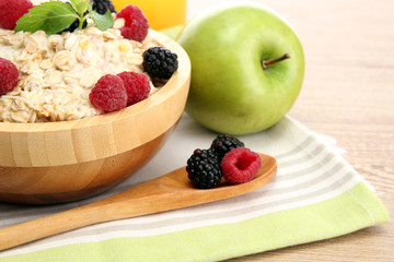 tasty oatmeal with berries and glass of juice, on wooden table