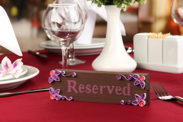 Reserved sign on restaurant table with empty dishes and glasses
