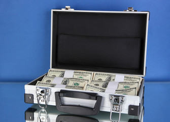Suitcase with 100 dollar bills on blue background