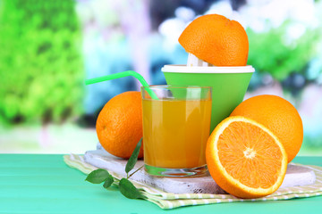 Citrus press, glass of juice and ripe oranges