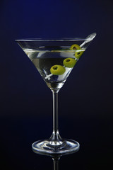 Martini glass with olives on dark blue background