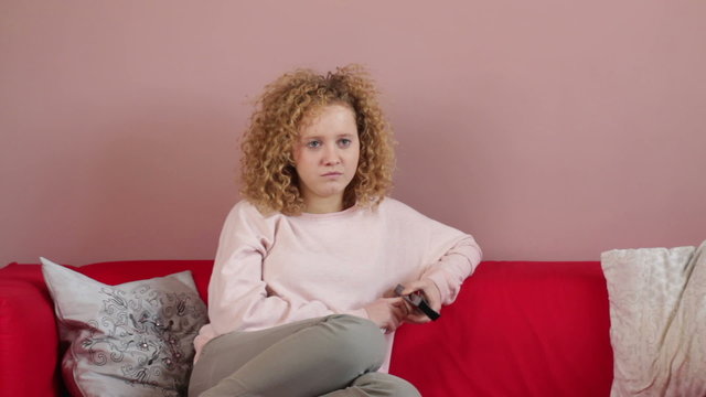 Young woman with remote control watching tv and crying